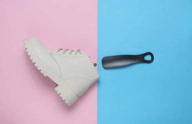 Women's white leather winter boot with shoehorn on a blue-pink background. Top view clipart