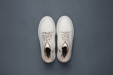 Koyu gri arka planda beyaz kadın deri botları. Üst görünüm