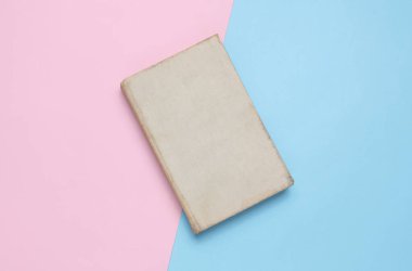 Mavi-pembe arka planda pejmürde kapağı olan eski bir kitap.