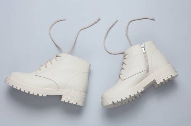 Gri arka planda beyaz kadın deri çizmeleri. Üst görünüm