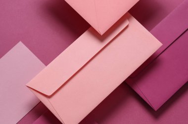 Pembe arka planda yüzen pembe tonlar zarflar ve kartlar. Davetiyeler, şirket kimlikleri.