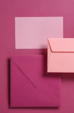 Pembe arka planda yüzen pembe renkli zarflar ve kart seti. Davetiyeler, şirket kimlikleri.