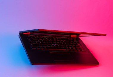 Mavi-pembe neon ışıkta süzülen modern dizüstü bilgisayar