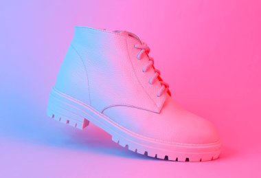 Mavi-kırmızı neon ışıkta süzülen beyaz deri çizme. Yaratıcı moda hala hayat