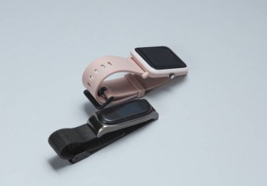 Gri arka planda modern akıllı saat ve bilezik.