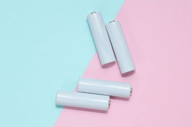 Mavi-pembe arka planda beyaz aa piller veya akümülatörler