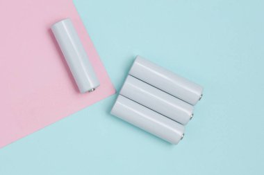Mavi-pembe arka planda beyaz aa piller veya akümülatörler