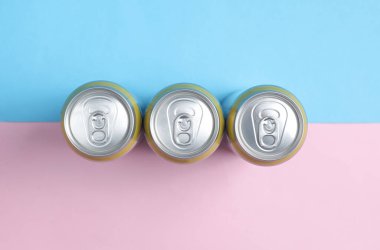 Mavi-pembe pastel arka planda metal bira kutuları. Üst görünüm