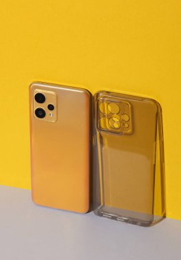 Üçlü kameralı sarı modern akıllı telefon ve renkli arka grund 'lu silikon çanta. Gadget koruması. Yaratıcı yerleşim