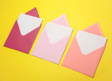 Sarı zemin üzerinde beyaz boş harfler olan pembe zarflar. Yaratıcı yerleşim