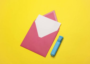 Beyaz, boş bir mektup ve sarı arka planda işaretli pembe bir zarf. Yaratıcı yerleşim