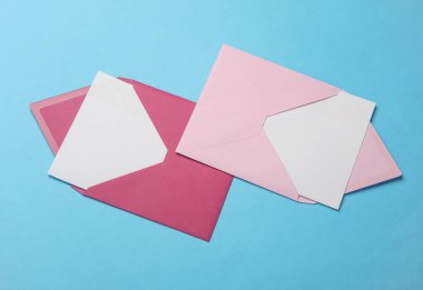 Üzerinde beyaz boş bir mektup ve mavi arka planda işaret olan pembe bir zarf. Yaratıcı yerleşim