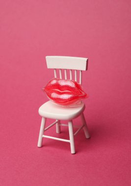 Sandalyede plastik dudaklar, pembe arka plan. Minimalizm. Güzellik konsepti