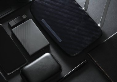 Modern siyah aletler ve aksesuarlar. Laptop, akıllı telefon, harici sabit disk, kablosuz ağ yönlendirici, USB flash disk, siyah arka planda güç bankası. Çalışma alanı. Düz yatıyordu. Üst görünüm