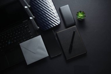 Akıllı telefonlu dizüstü bilgisayar, defter, zarf ve siyah arka planda kablosuz ağ yönlendirici. Düz yatıyordu. Çalışma alanı