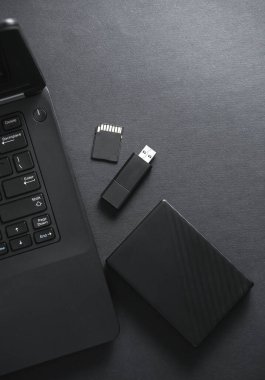 Harici sabit disk, flash disk ve siyah arka planda dizüstü bilgisayarı olan SD kart