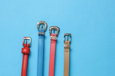Mavi arka planda kadın deri kemerleri. Moda aksesuarları. Düz yatıyordu. Üst görünüm