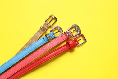 Sarı arka planda kadın deri kemerler. Moda aksesuarları. Düz yatıyordu. Üst görünüm