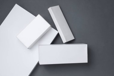 Koyu gri arka plandaki sunum ürünleri için beyaz karton kutuların farklı şekilleri. Tasarım için maket. Üst görünüm