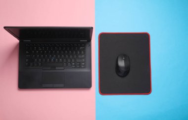 PC fare altlığı ve pembe mavi arka planda siyah dizüstü bilgisayar ve bilgisayar faresi
