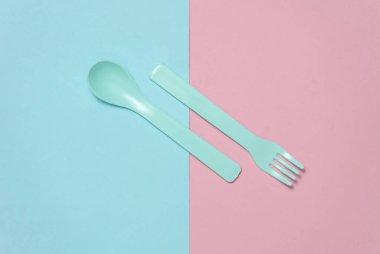 Pembe arka planda bebek için plastik çatal ve kaşık. Üst görünüm