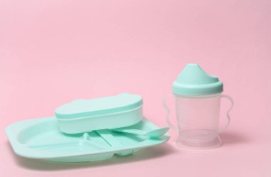 Pembe arka planda bir bebeği beslemek için plastik tabaklar