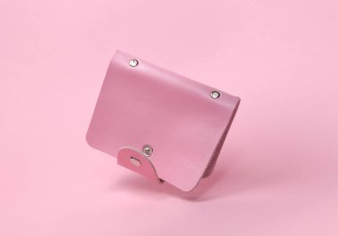Pembe deri kart tutucu pembe bir arka planda yüzüyor.