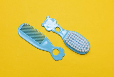 Sarı arka planda yeni doğan bebek için taraklar ve saç fırçası