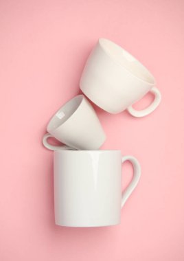 Pembe arka planda üç beyaz seramik bardak.