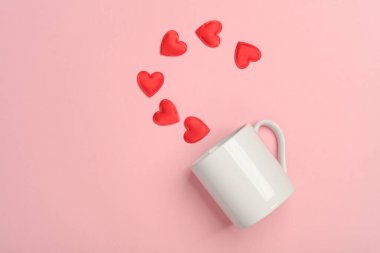 Pembe arka planda kalpleri olan seramik bardak. Sevgililer Günü konsepti
