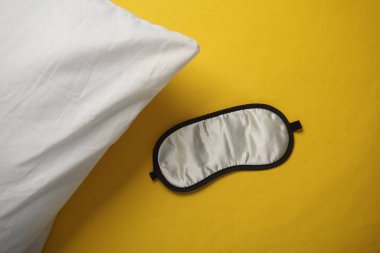 Sarı arka planda yastıklı uyku maskesi. Sağlıklı uyku konsepti