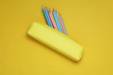 Sarı arka planda renkli kalemleri olan bir okul kalem kutusu. Okul konseptine dönelim.