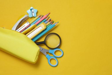 Sarı arka planda kırtasiye malzemesi ve okul aksesuarları olan sarı kalem kutusu. Okul konseptine geri dönelim. Üst Manzara. Düz yatıyordu