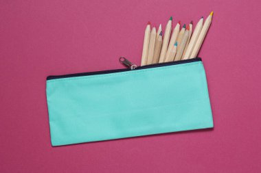 Pembe arka planda renkli kalemleri olan bir okul kalem kutusu. Okul konseptine dönelim.