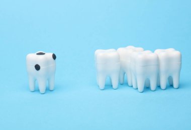 Mavi arka plandaki bakirelerden etkilenen bir diş modeli. Diş tedavisi