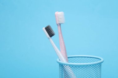 Mavi arka planda sepette iki diş fırçası.