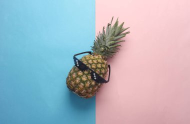 Pembe mavi arka planda güneş gözlüklü ananas. Yaz havası. Üst görünüm