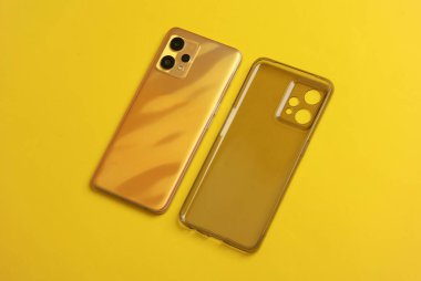Sarı arka planda silikon koruyucu çantalı akıllı telefon.