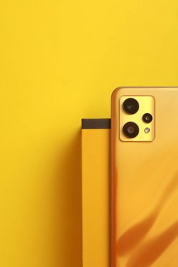 Sarı arka planda kutusu olan modern bir akıllı telefon. Üst görünüm