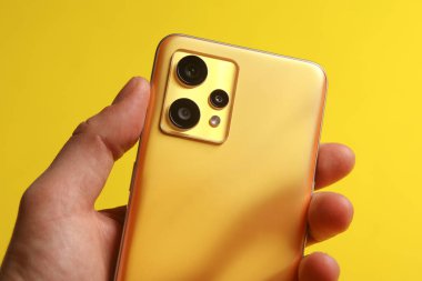 El, üç kameralı modern bir akıllı telefonu tutuyor.