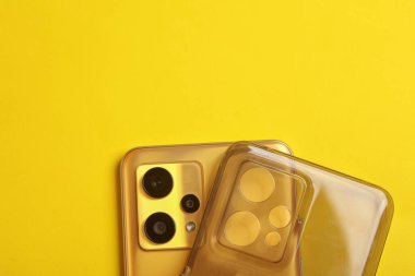 Sarı arka planda silikon koruyucu çantalı akıllı telefon.