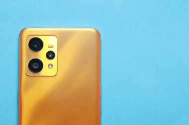 Mavi arka planda modern bir akıllı telefonun üç kamerası.