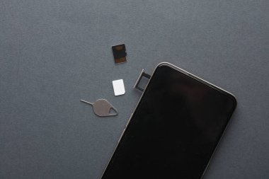 Akıllı telefon, üzerinde SIM ve gri arka planda mikro SD hafıza kartları olan tepsi. Düz yatıyordu
