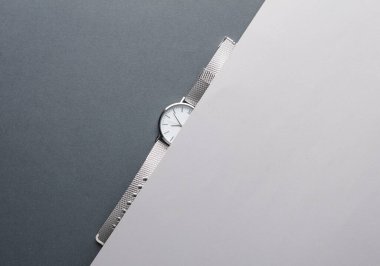 Gri arka planda metal veya gümüş kayışlı kadın bileği analog saati. Düz yatıyordu. Üst görünüm