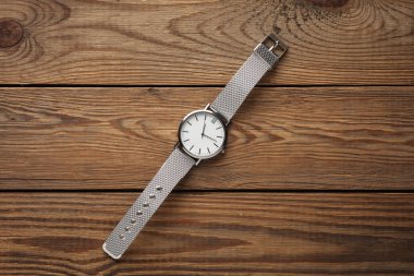 Ahşap arka planda metal veya gümüş kayışlı kadın bileği analog saati.