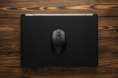 Ahşap arka planda bilgisayar faresi olan bir laptop. Üst Manzara. Düz yatıyordu