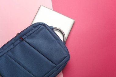 Pembe arka planda dizüstü bilgisayarı olan bir sırt çantası. Üst görünüm