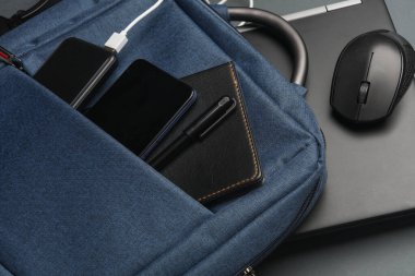 Çalışma için modern cihazları ve aksesuarları olan dizüstü bilgisayar koyu gri arka planda sırt çantasında. Üst Manzara. Düz yatıyordu