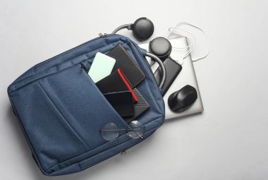 Çalışma için modern aygıtlara ve aksesuarlara sahip dizüstü bilgisayar beyaz arka planda sırt çantasında çalışmaktadır..