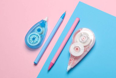 Pembe arkaplanda bant düzelticiler ve kalemler. 